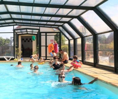Piscine couverte avec baigneurs et transats au Camping Les Vertes Feuilles