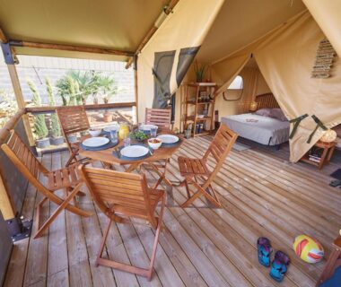 Terrasse en bois avec table et chaises devant tente glamping au Camping Les Vertes Feuilles
