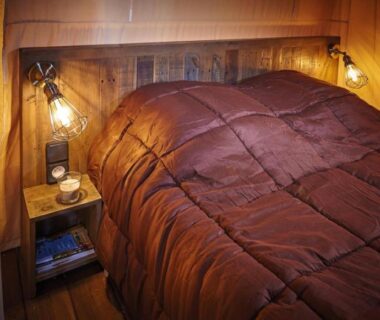 Intérieur de chambre avec lit et lampe au Camping Les Vertes Feuilles
