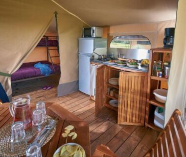 Intérieur de tente avec coin cuisine et table au Camping Les Vertes Feuilles