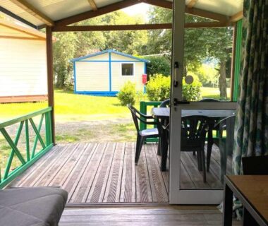 Terrasse couverte avec table et chaises donnant sur pelouse du Camping L'oasis du Berry