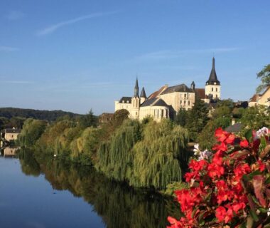 Bord de rivière avec village, église et fleurs au Camping L'oasis Du Berry