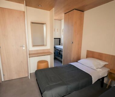 Chambre avec deux lits simples et coiffeuse au Camping Lou Broustaricq