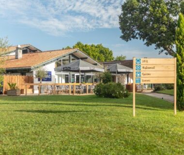 Terrasse et panneau d'accueil sur pelouse au Camping Lou Broustaricq