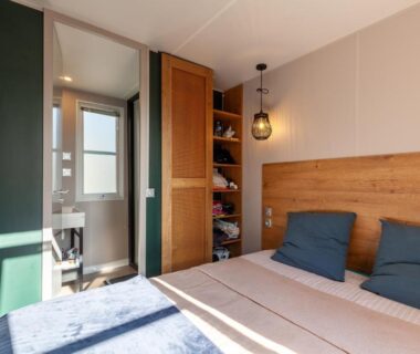 Chambre double lumineuse avec armoire ouverte et salle d'eau visible au Camping Lou Soulei 218