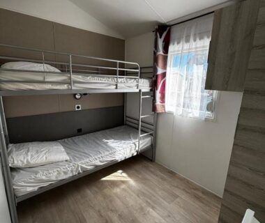 Chambre avec lits superposés et fenêtre au Camping Mar Estang