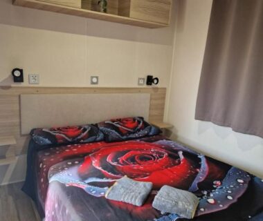Chambre avec lit double et couette motif rose dans le mobil-home du Camping Mar Estang