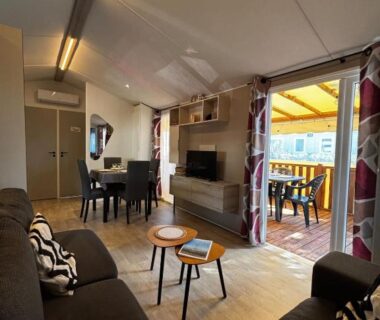 Salon intérieur avec canapés table à manger et terrasse ouverte au Camping Mar Estang