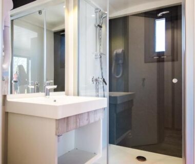 Salle de bains avec cabine de douche et lavabo au Camping Mas De Pierredon