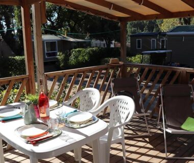 Terrasse couverte avec table dressée et chaises au Camping Mas De Pierredon