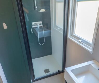 Salle de bain avec cabine de douche vitrée et lavabo au Camping Mas du Padre
