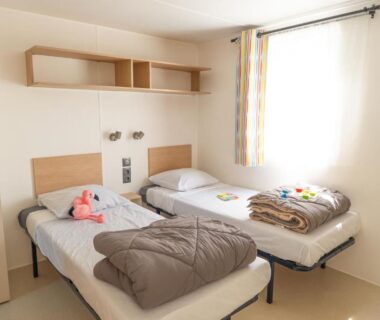 Chambre intérieure avec deux lits simples au Camping Mas du Padre