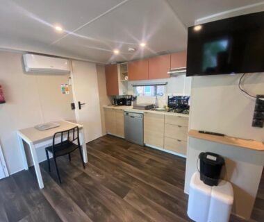Intérieur de mobil home avec kitchenette télévision et coin repas au Camping Mayotte