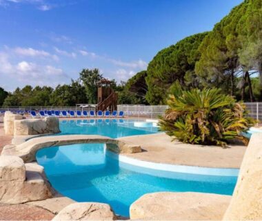 Piscine extérieure avec transats et pins au Camping Montana Parc 5 étoiles