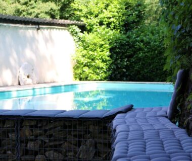 Piscine et banquette coussinée au bord du mur végétal du Camping Moulin De Chaules