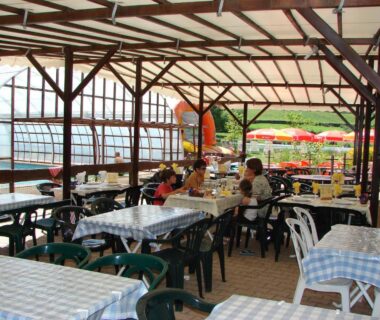 Terrasse couverte avec tables et chaises au Camping Moulin de Collonge