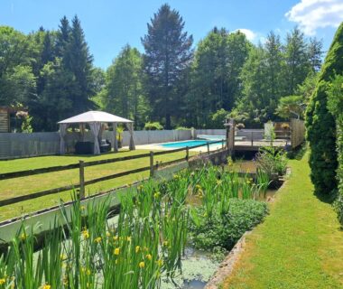Espace piscine avec tonnelle et petit étang au Camping Moulin du Pommier