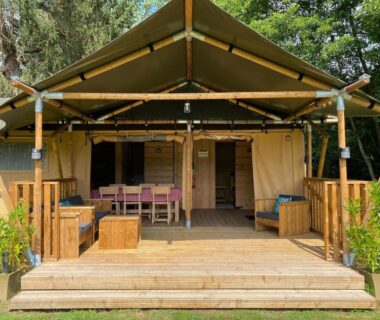 Terrasse en bois avec coin salon et table sur lodge au Camping Moulin du Pommier