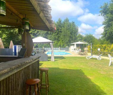 Pelouse et piscine extérieure avec bar et transats au Camping Moulin du Pommier
