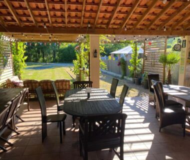 Terrasse couverte avec tables et chaises du Camping Moulin du Pommier