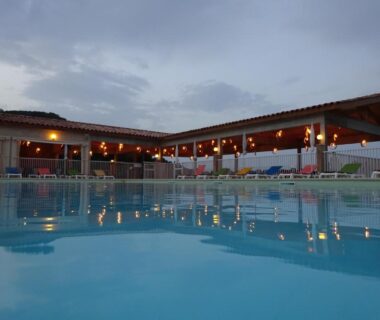 Piscine éclairée au crépuscule devant la terrasse du Camping Mozziconaccio