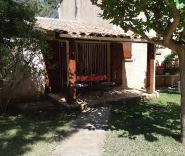 Terrasse de bungalow ombragée avec banc et pelouse au Camping Mozziconaccio
