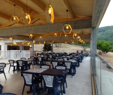 Terrasse couverte avec tables et chaises vue sur colline au Camping Mozziconaccio