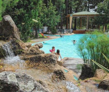 Piscine extérieure avec cascade et végétation au Camping Mulinacciu