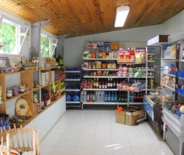 Intérieur de la boutique avec étagères de produits et réfrigérateur au Camping Naturiste Tikayan Petit Arlane