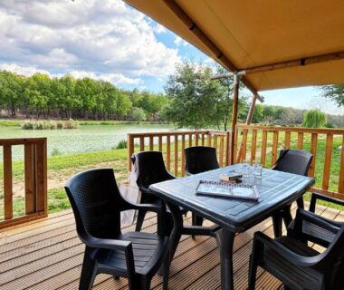 Terrasse au bord de l'étang avec table et chaises au Camping Naturiste Tikayan Petit Arlane