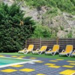 Piscine extérieure bordée de transats jaunes au Camping New Rabioux
