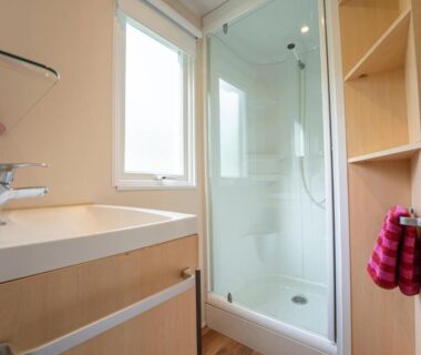 Salle de bain avec douche cabine et lavabo au Camping New Rabioux