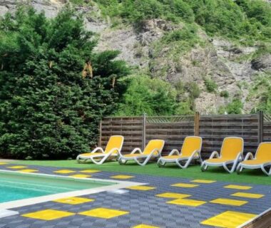 Piscine extérieure bordée de transats jaunes au Camping New Rabioux