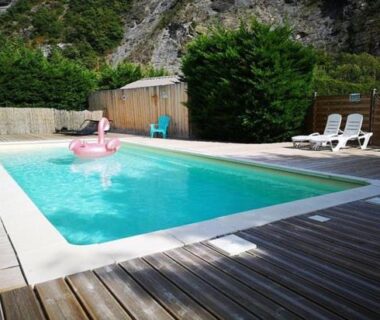 Piscine extérieure avec transats et bouée flamant sur terrasse en bois au Camping New Rabioux