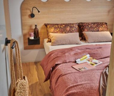 Chambre avec lit double et tête de lit en bois dans le Camping O'Aka