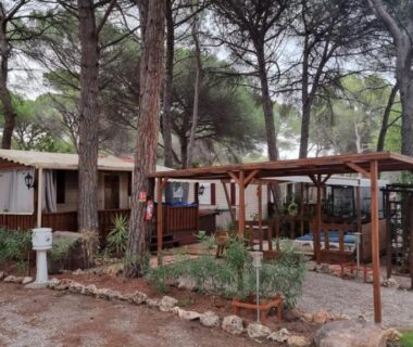 Emplacement ombragé avec mobilhome et terrasse en bois au Camping Oasis Village