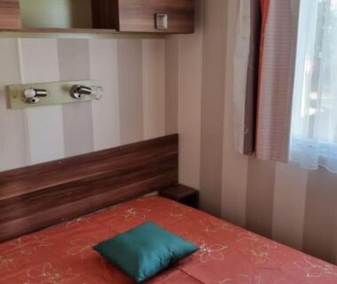 Chambre avec lit double coussin vert et fenêtre dans le mobil home Oasis Village