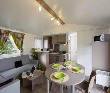 Séjour avec table dressée et kitchenette dans le Camping Officiel Siblu Domaine de Soulac