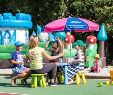 Aire de jeux extérieure avec enfants et château gonflable au Camping Officiel Siblu Domaine de Soulac