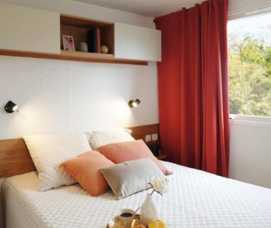 Chambre avec lit double et rideaux rouges au Camping Officiel Siblu Les Dunes de Contis