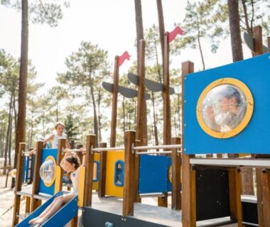 Aire de jeux en pinède avec toboggan et structure bois au Camping Officiel Siblu Les Dunes de Contis