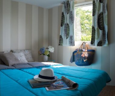Chambre avec lit turquoise et fenêtre dans le mobil-home du Camping Officiel Siblu Mar Estang