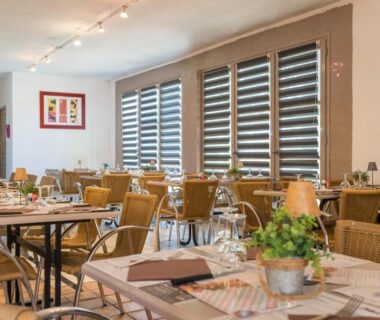 Salle à manger avec tables dressées et chaises dans le restaurant du Camping Officiel Siblu Mar Estang