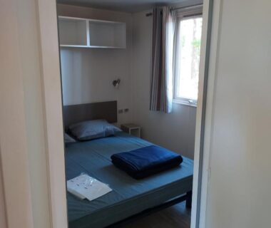 Chambre avec lit et fenêtre dans le mobil-home du Camping Onlycamp Le Petit Bocage