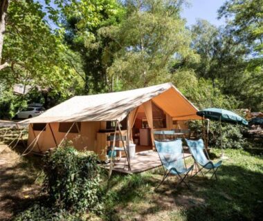 Emplacement ombragé avec tente lodge et chaises pliantes au Camping Onlycamp Le Petit Bocage