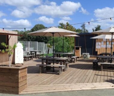 Terrasse extérieure avec parasols et tables au Camping Onlycamp Le Petit Bocage