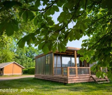 Terrasse en bois et jardin d'un chalet moderne au camping Onlycamp Le Pont Romain
