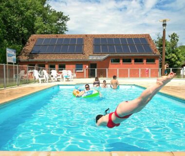 Piscine extérieure avec plongeon et baigneurs au camping Onlycamp Le Pont Romain