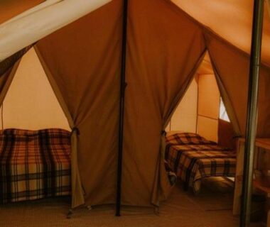 Intérieur de tente avec deux lits et plaids à carreaux au Camping Onlycamp Le Pont Romain