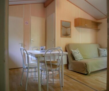 Intérieur du mobil-home avec coin repas et canapé du Camping Onlycamp Le Pré
